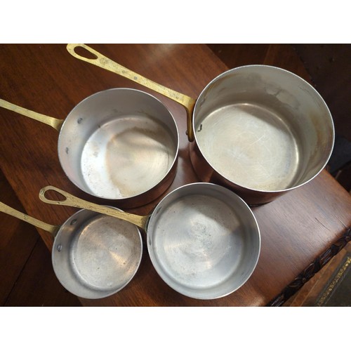 665A - Four graduated copper pans with brass handles, largest diameter 16.5cm