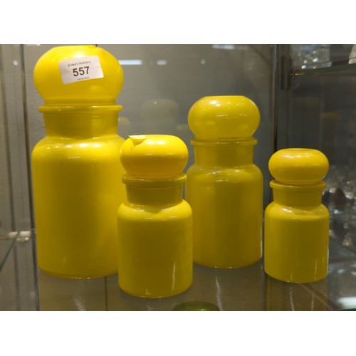 557 - Collection of four bright yellow glass storage containers, largest 22 cm high smallest 13 cm high