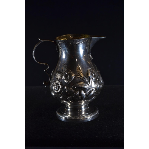 359 - George III silver cream jug, rubbing to London hallmarks, embossed with flowers and vacant cartouche... 