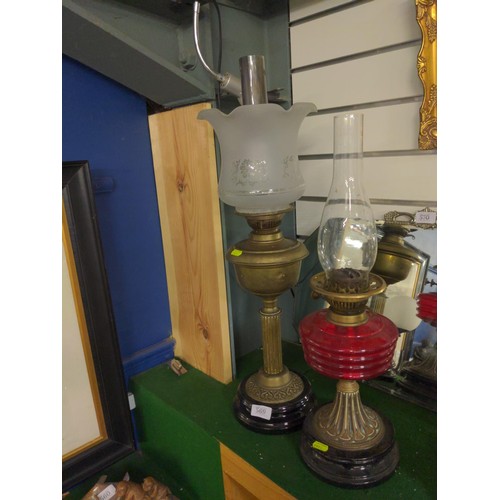 569 - 2 oil lamps. One with red glass reservoir and one brass. One shade missing and one mismatched. Heigh... 