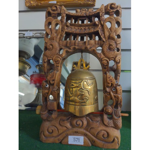 571 - Brass temple bell in carved frame. Height 36cm