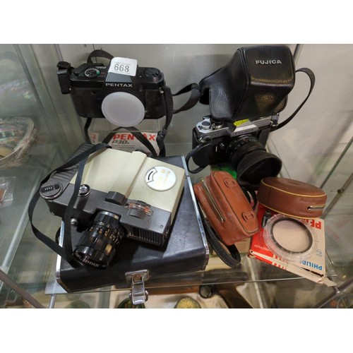 668 - Two shelves of vintage camers and equipment, inc, Pentax P30, Fujica xt605 and a Sonu handycam, plus... 