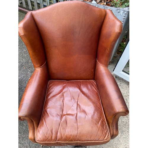 448 - Chocolate brown wing back armchair with front castors and stud finishing detail.