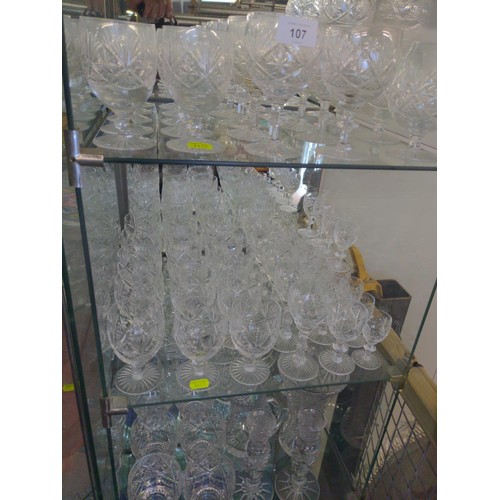 107 - Cut Glass over 3 shelves inc glasses, candlesticks & jugs etc