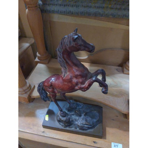 321A - A metal figure of a rearing stallion finished in bronze colour on wooden plinth. Height 38 cm