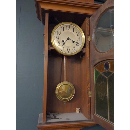 354 - Mahogany cased wall clock with brass face and brass pendulum and features a stained glass viewing pa... 