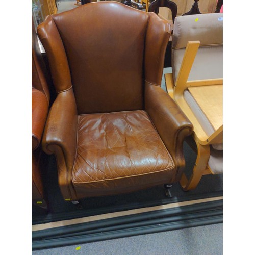 448 - Chocolate brown wing back armchair with front castors and stud finishing detail.