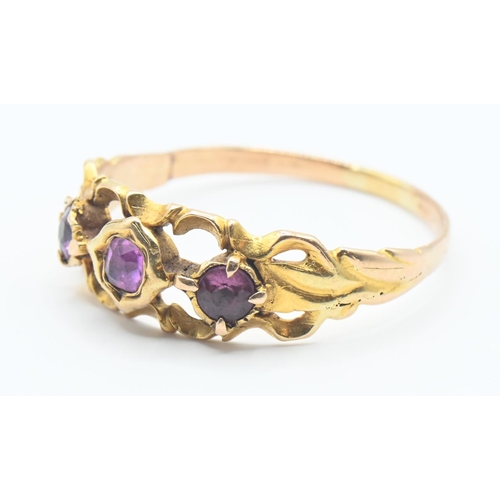 128 - Yellow metal three stone ring set with central pink sapphire and flanked with two paste stones. Size... 