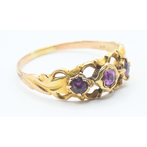 128 - Yellow metal three stone ring set with central pink sapphire and flanked with two paste stones. Size... 