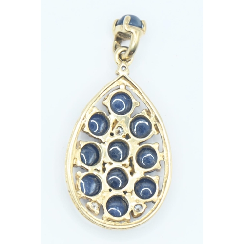 157 - Yellow metal sapphire and diamond pendant, tests positive for 14ct gold. Set with eleven cabochon sa... 