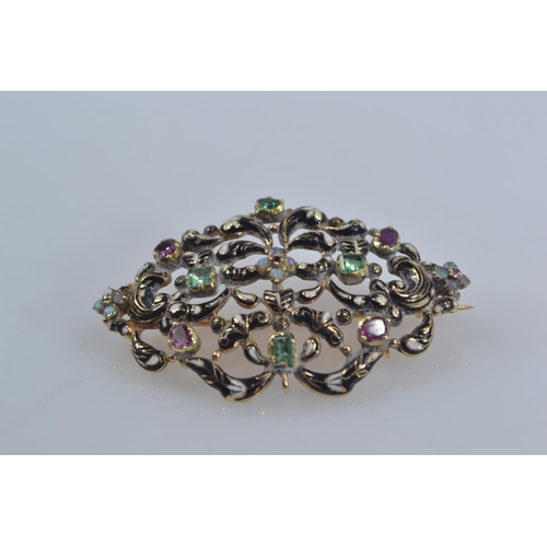 158 - European scrolled Yellow metal brooch with black and white enamel detail. Set with opal, emeralds &a... 