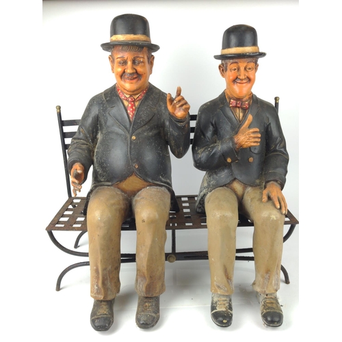 502 - Stan Laurel and Oliver Hardy resin models sat on a metal  garden bench, 57cm wide, 40cm deep and 60c... 