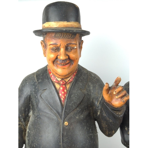 502 - Stan Laurel and Oliver Hardy resin models sat on a metal  garden bench, 57cm wide, 40cm deep and 60c... 