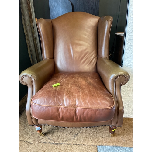 1177 - Laura Ashley 'Southwold' leather wing back arm chair. Has turned legs and front brass castors.