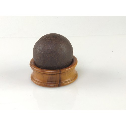 1019 - Cast iron canon ball, dia. 5cm, on wooden napkin ring