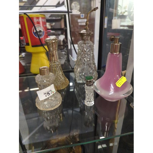 787 - Four crystal scent bottles with silver tops together with one pink studio glass bottle