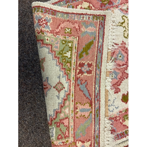 526 - Two hand finished wool rugs predominantly in pink shades with cream background. W69 L126cm