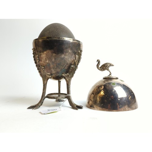 438 - An empire style silver plated egg coddler surmounted by an emu finial and standing on three birds fo... 