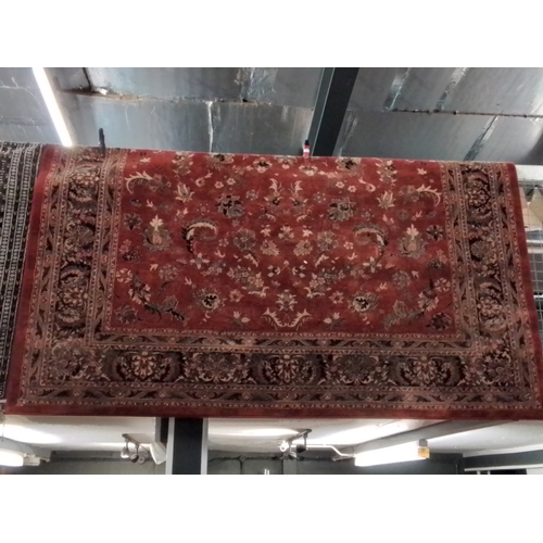 132 - Large 100% wool floral design rug; red and greens with large border; made in Belgium. 340 x 240 cm