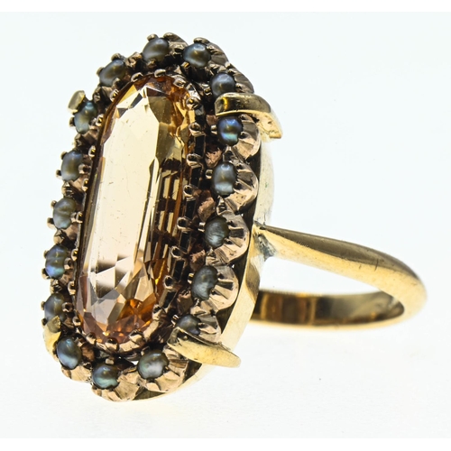 88 - Imperial topaz ring. Central stone (15mm x 6mm) is surrounded by a halo of seed pearls and set in ye... 