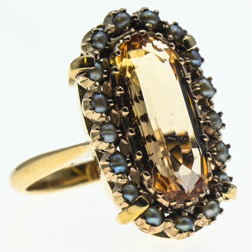 88 - Imperial topaz ring. Central stone (15mm x 6mm) is surrounded by a halo of seed pearls and set in ye... 