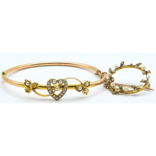 127 - Yellow metal and seed pearl set bangle with a heart and leaf design testing positive for 14ct gold. ... 