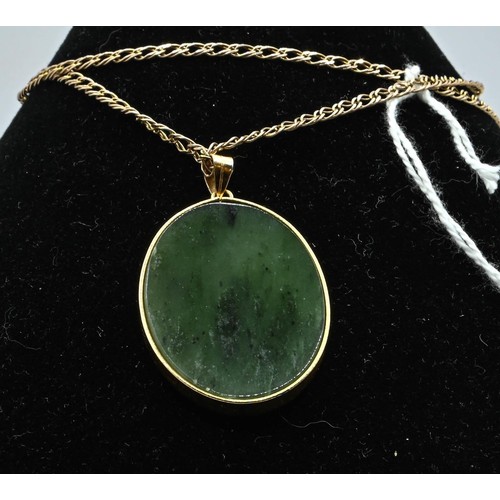 129 - Jade pendant with Chinese character & yellow metal surround on a 9ct gold chain, length 55 cms, ... 