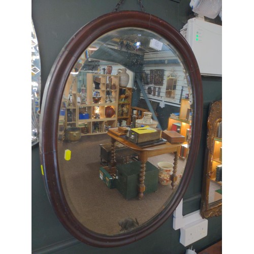 115 - Oval bevelled wood framed mirror on chain, 57 x 73 cms