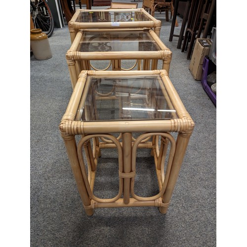 715 - Nest of three bamboo tables with glass tops.