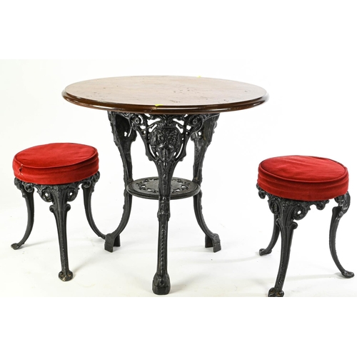 64 - Pub style heavy cast iron based pedestal table with 2 cast base stools. Table D76cm H70cm