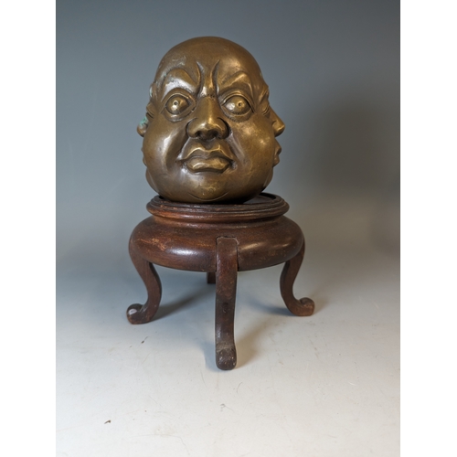 467 - Four sided Buddha head, character marks to the base brass, on a wooden stand. total height 22cm appr... 