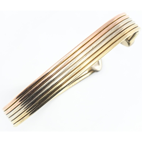 125 - 9ct gold tri-colour gold cuff bracelet, of ribbed design with C-shaped terminals, inner width approx... 