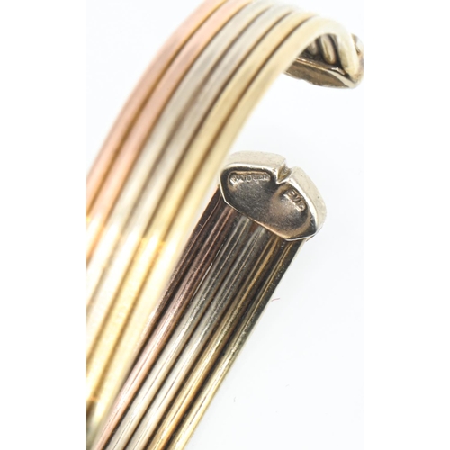 125 - 9ct gold tri-colour gold cuff bracelet, of ribbed design with C-shaped terminals, inner width approx... 