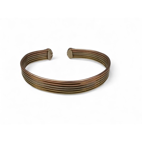 125 - 9ct gold tri-colour gold cuff bracelet, of ribbed design with C-shaped terminals, inner width approx... 