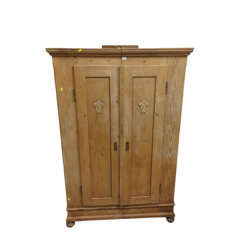 640 - Strip pine, double door wardrobe. With relief emblems to both doors. On bun feet. W120cm, D57cm, H18... 