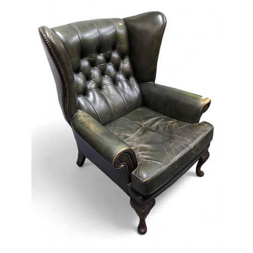 548 - Green leather button back wingback armchair. Damage to one arm