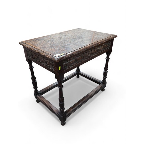 577 - A heavily carved oak occasional table, with box stretched turned supports. W78cm D52cm H71cm