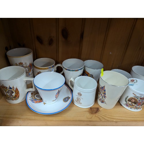 679 - Commemorative ware over three shelves, inc. Clarice Cliff Coronation teacup and saucer, Royal Crown ... 