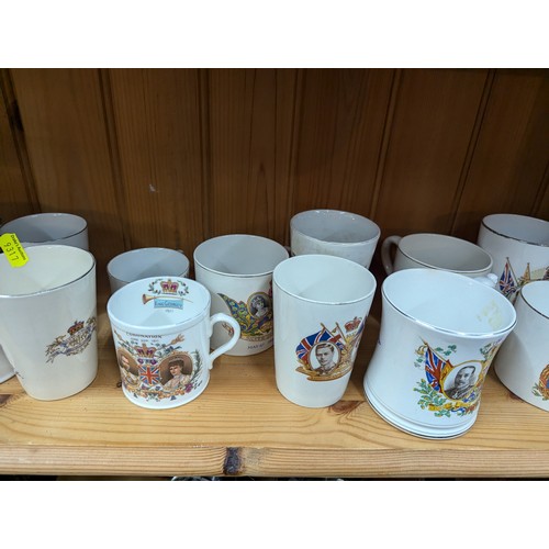 679 - Commemorative ware over three shelves, inc. Clarice Cliff Coronation teacup and saucer, Royal Crown ... 