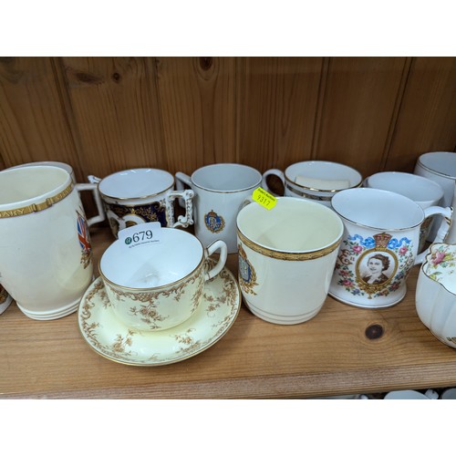 679 - Commemorative ware over three shelves, inc. Clarice Cliff Coronation teacup and saucer, Royal Crown ... 