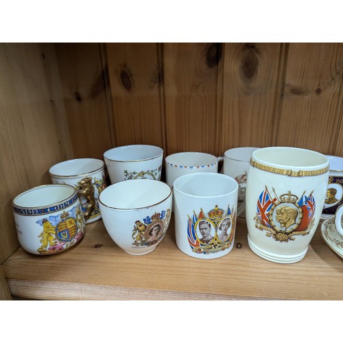 679 - Commemorative ware over three shelves, inc. Clarice Cliff Coronation teacup and saucer, Royal Crown ... 