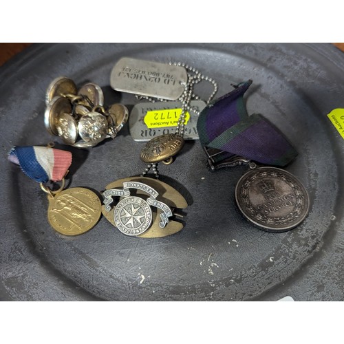 387A - Pewter plate with various militaria inc: ERII campaign medal, dogtags, military buttons and badges.