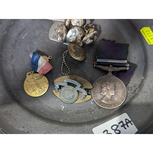 387A - Pewter plate with various militaria inc: ERII campaign medal, dogtags, military buttons and badges.