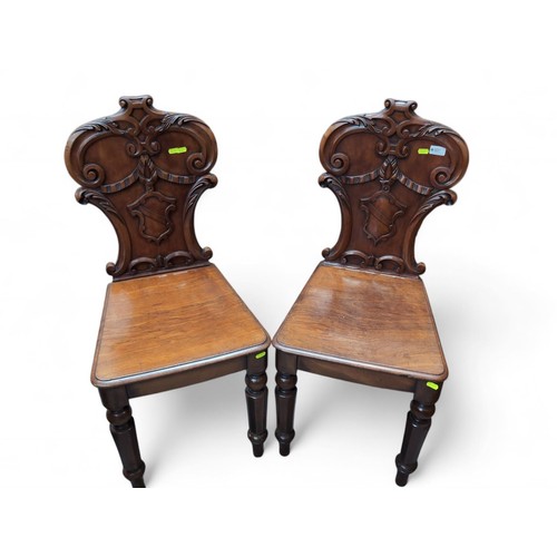 107 - Pair of carved mahogany hall chairs.