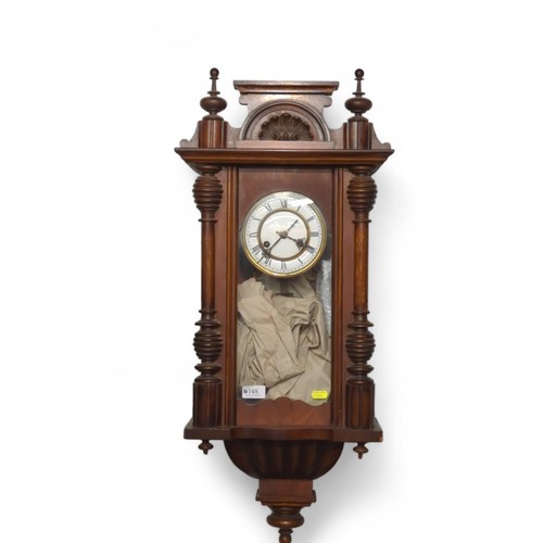 148 - Oak cased wall clock with pendulum and key, top finial detached but present W32 x D16 x H84cm