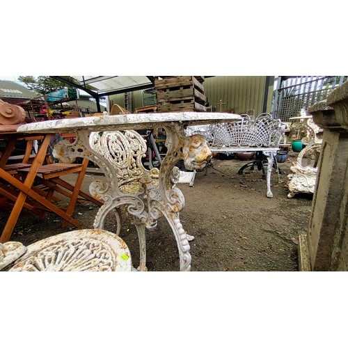 591 - Early C.20th cast iron table and 2 chairs with lion's head detail to table base. Table diameter 68cm... 