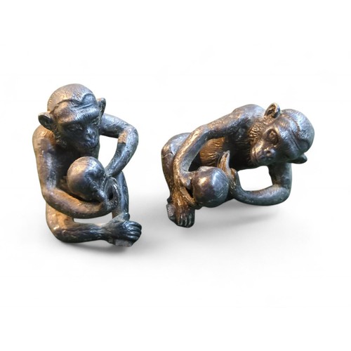 410 - 2 metal chimps holding human skulls. H6cm.