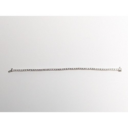 97 - 14ct white gold diamond line bracelet, comprising an articulated line of 56 claw-set brilliant-... 