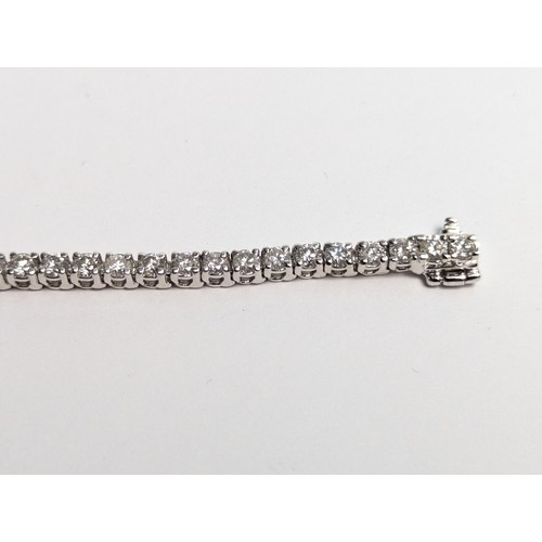 97 - 14ct white gold diamond line bracelet, comprising an articulated line of 56 claw-set brilliant-... 