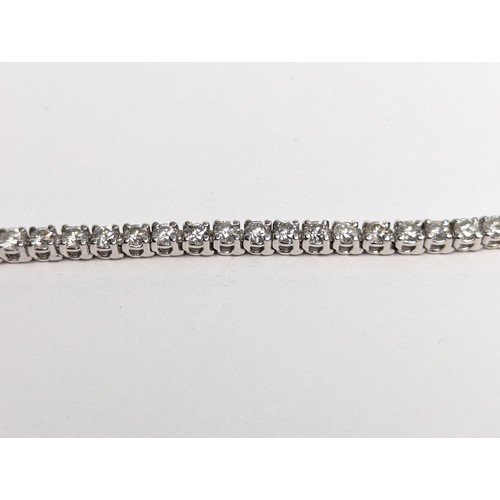 97 - 14ct white gold diamond line bracelet, comprising an articulated line of 56 claw-set brilliant-... 